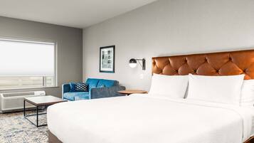 Ein Hotelzimmer mit einem großen Bett, einem blauen Sofa, einem kleinen Tisch und einer Wandlampe.