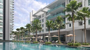 Un hotel moderno con piscina, palmeras y tumbonas.