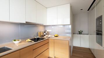 A modern kitchen with white cabinets, a wooden countertop, and a built-in oven.