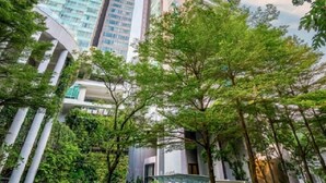 Un moderno complejo de edificios con torres residenciales altas, un patio central con árboles y un cartel que dice