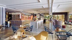 Un café moderne avec des chaises bleues, un comptoir à café et un mur à rayures.