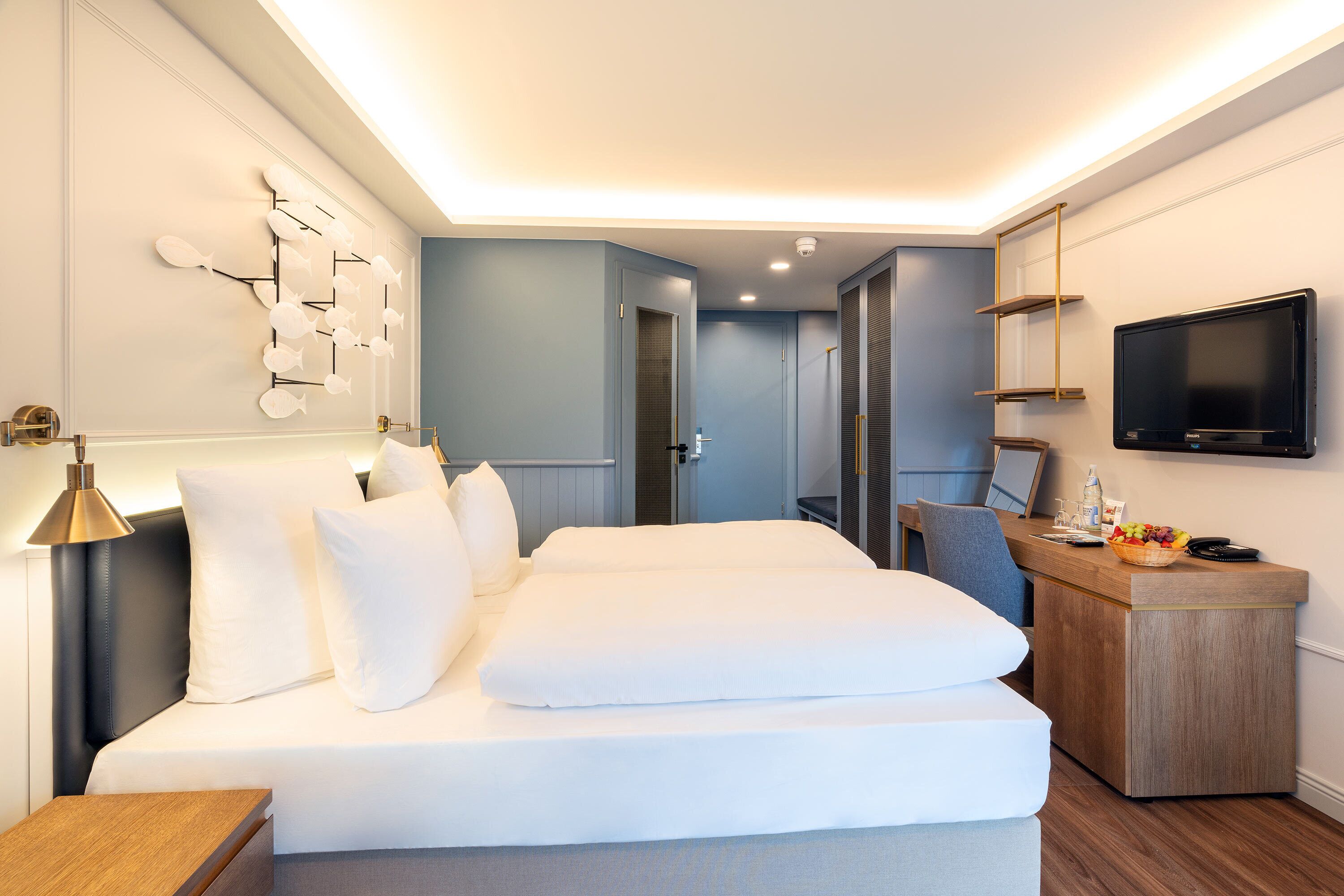 Een moderne hotelkamer met een groot bed, een bureau met een televisie en een wandplank.