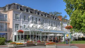 Un hôtel doté d’une véranda en verre, d’un espace extérieur aménagé et de jardinières fleuries.