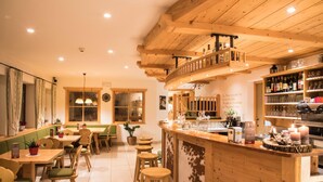 Ein gemütliches Restaurant mit Holztischen, einer Bar und einer hohen Holzbalkendecke.