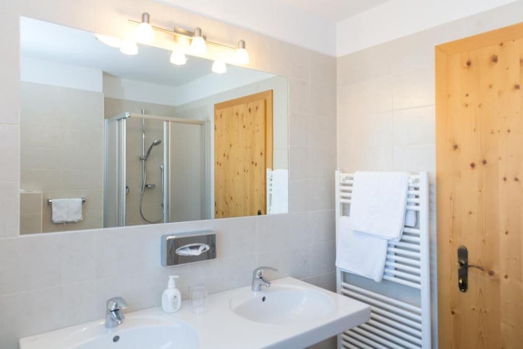 Un baño moderno con dos lavamanos, un espejo y una ducha.