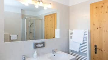 Un baño moderno con dos lavamanos, un espejo y una ducha.