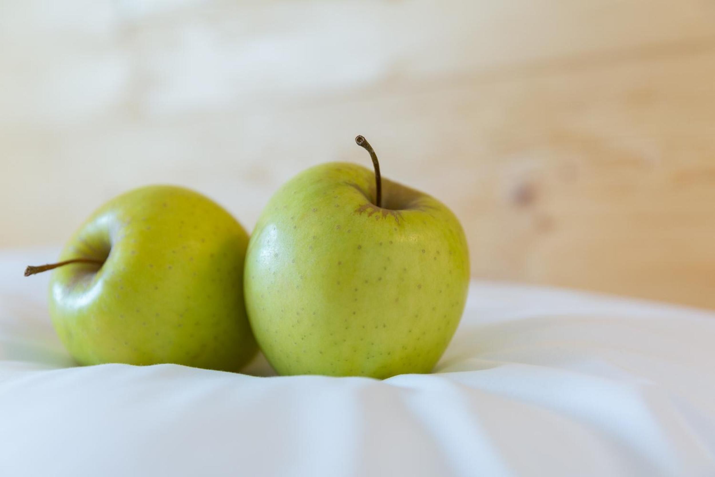 Two green apples on a white surface.