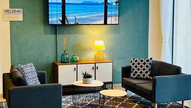 Een moderne woonkamer met uitzicht op zee, een houten kast, een lamp en twee banken.