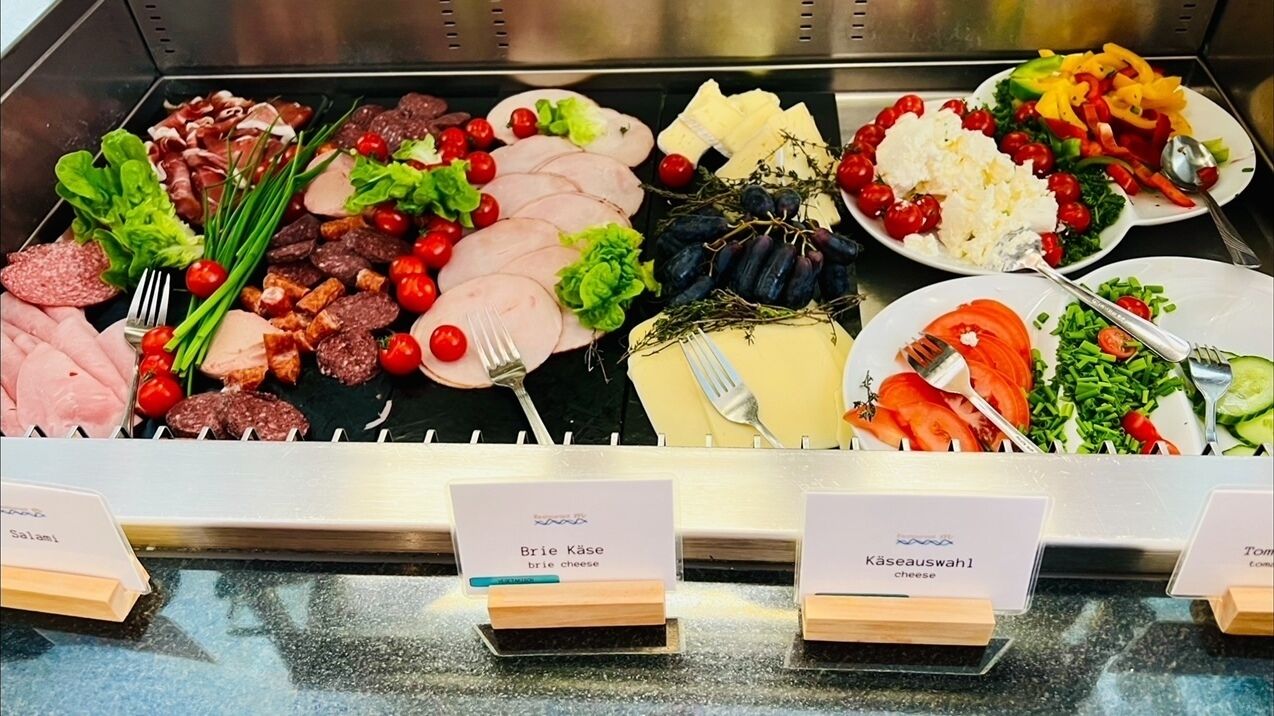 A buffet with various food items including meats, cheeses, and vegetables.