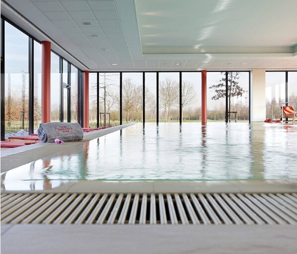 A spacious indoor swimming pool with large windows and a view of the outdoors.