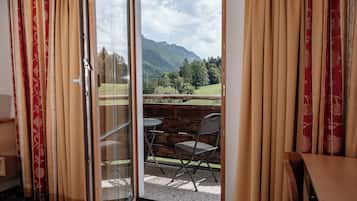 Una habitación con puerta de cristal corredera que da a una zona de estar exterior con vistas a las montañas.