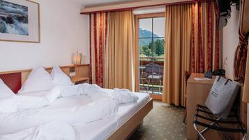 Habitación de hotel con cama, escritorio y silla. Hay una ventana con cortinas y vistas al exterior.