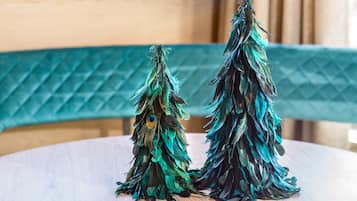 Deux petits sapins de Noël décoratifs, faits de plumes, sont posés sur une table ronde en bois.