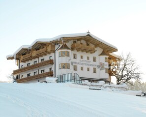 A snow-covered building with balconies and a sign reading "GASTHOF MARIASTEINERHOF". - Hotel Mariasteiner Hof (Mariastein)