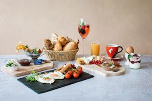 A breakfast setting with bread, eggs, tomatoes, cheese, and a drink. - Hotel Mariasteiner Hof (Mariastein)