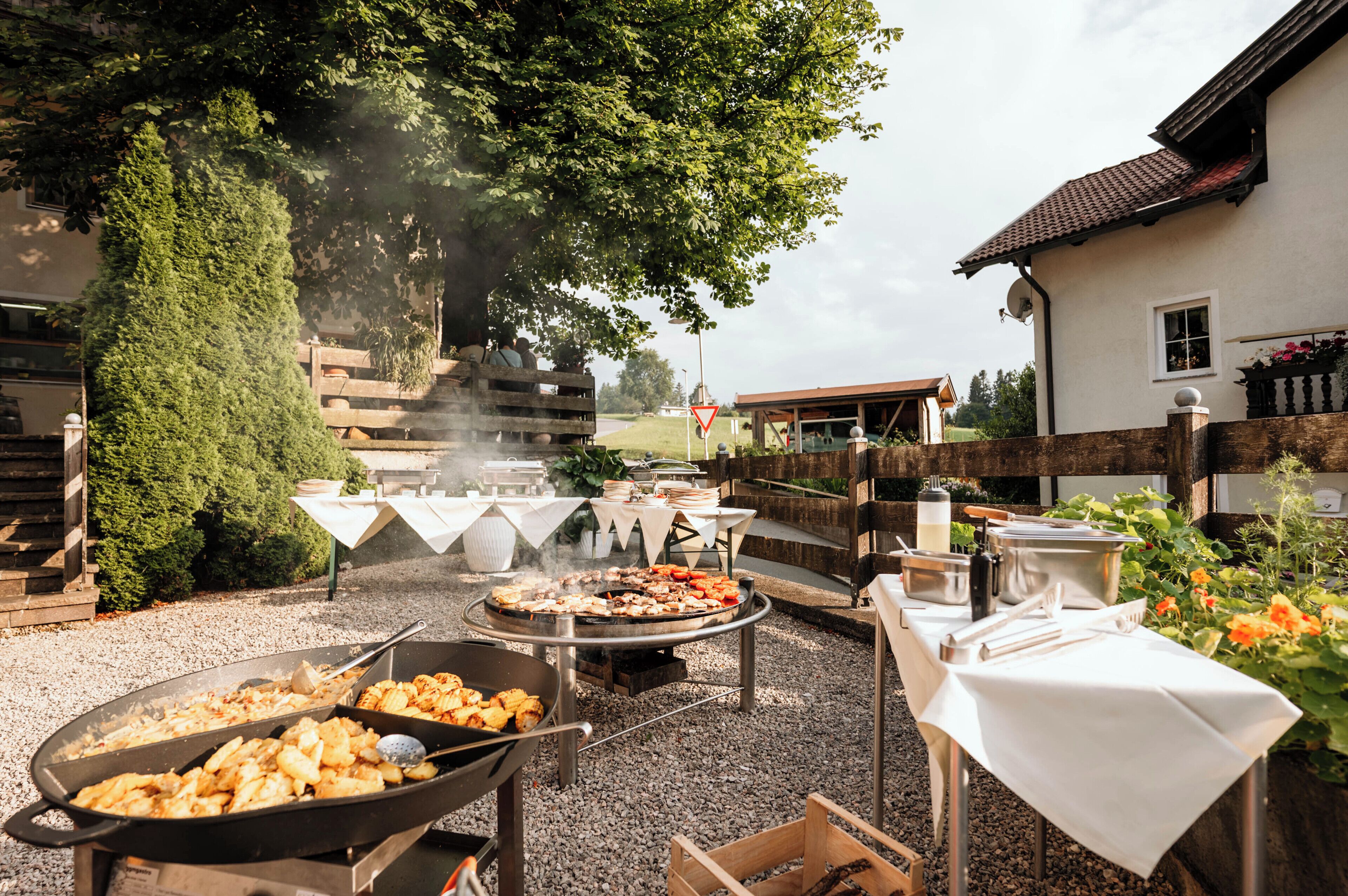 An outdoor barbecue setup with a grill, cooking utensils, and a table with food.
