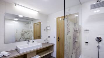 Une salle de bain moderne avec un grand miroir, un lavabo, une douche et un meuble-lavabo en bois.