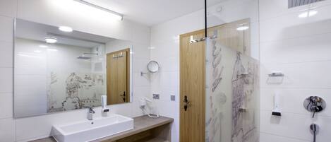 Un baño moderno con un espejo grande, un lavabo, una ducha y un mueble de tocador de madera.