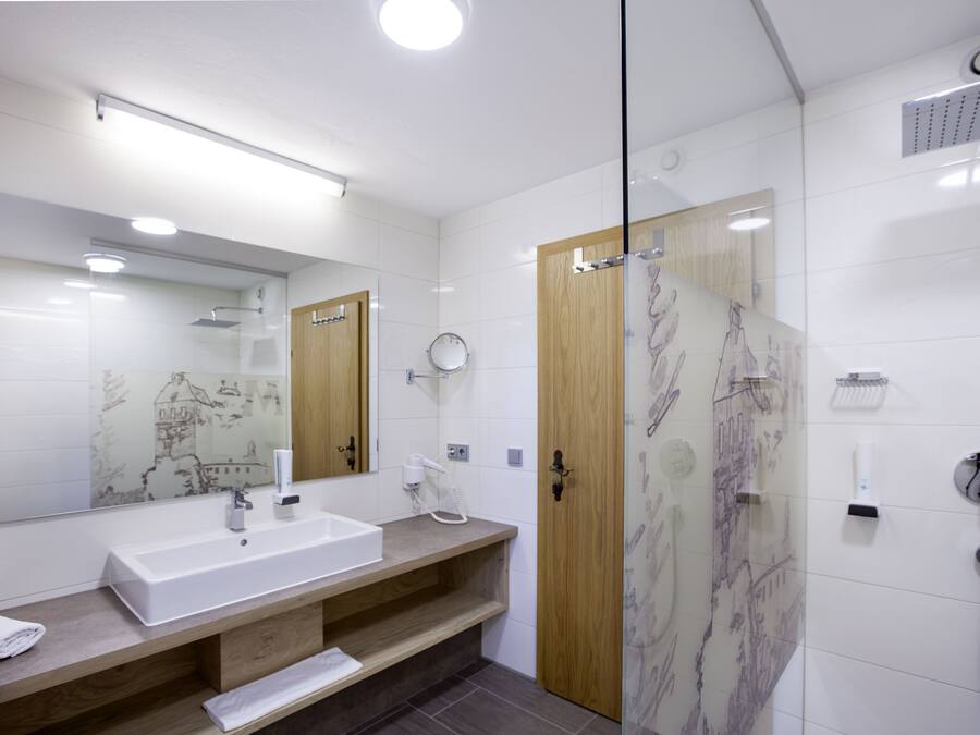 Une salle de bain moderne avec un grand miroir, un lavabo, une douche et un meuble-lavabo en bois.