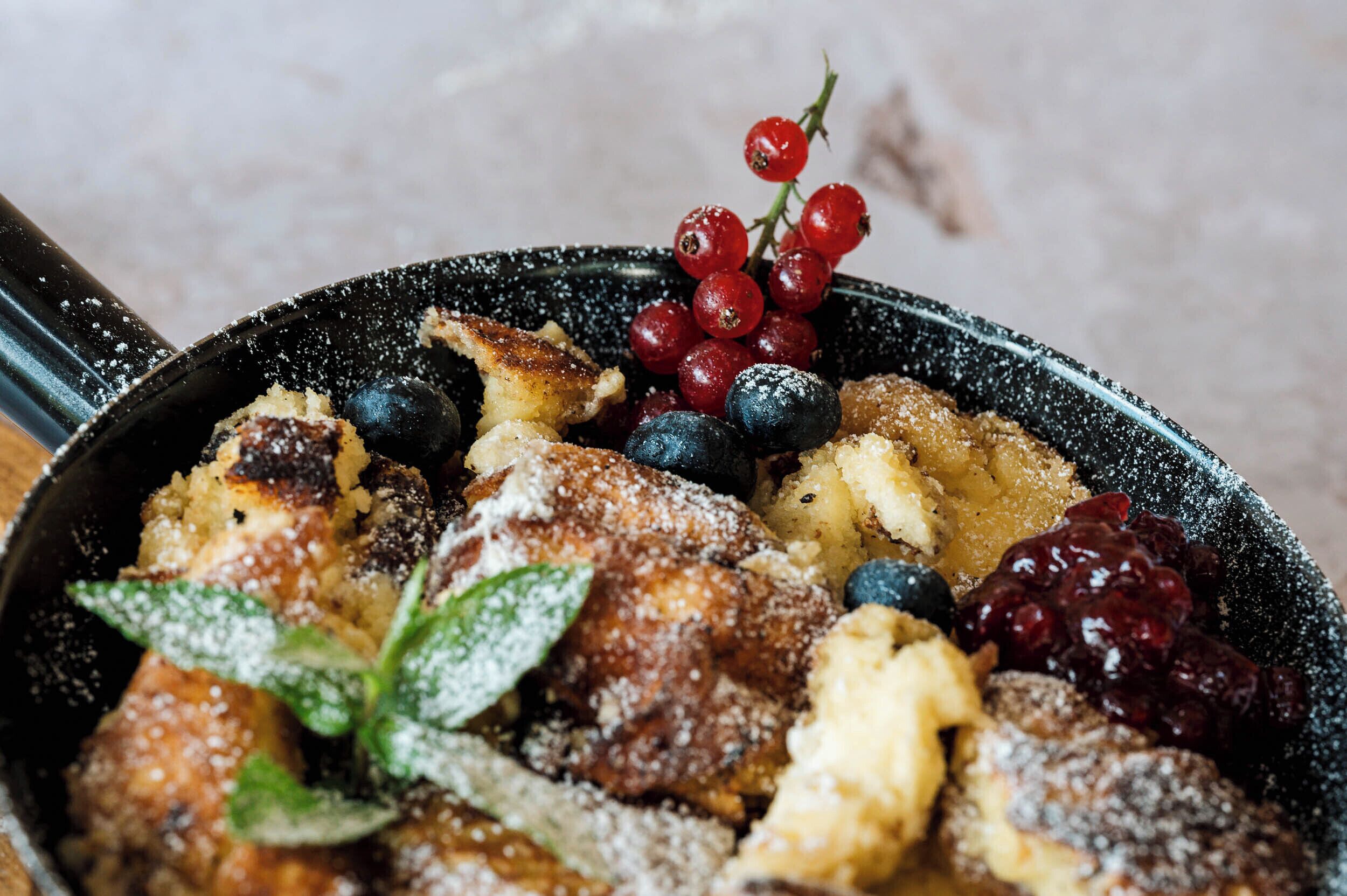 A close-up of a dish with breaded items, berries, and a mint leaf.
