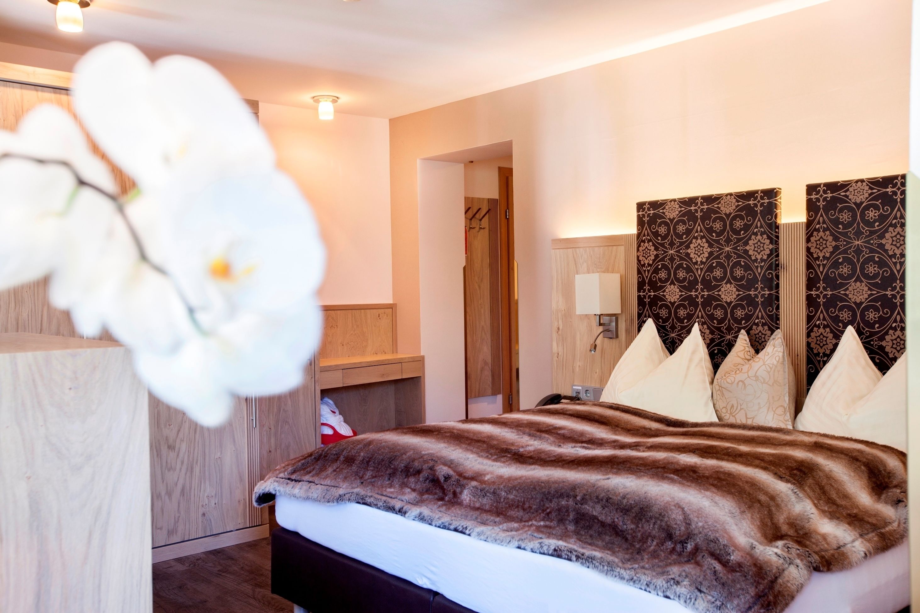 A modern bedroom with a large bed, wooden headboard, and a decorative wall panel.