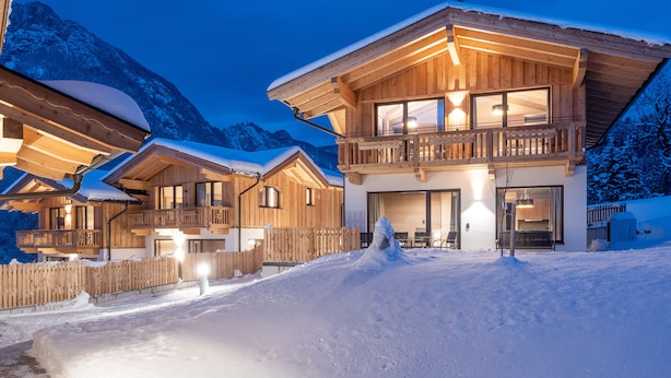 A wooden chalet with a balcony, large windows, and a snow-covered roof. - Hotel Mariasteiner Hof (Mariastein)