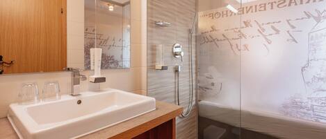 A modern bathroom with a large white sink, a mirror, and a glass-enclosed shower area.