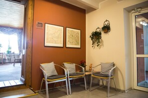 A reception area with three chairs, a small table with a vase, and two framed maps on the wall. - Hotel Zum Grunewald (Dinslaken)