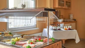 Una mesa de buffet con diferentes carnes, quesos y frutas.