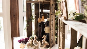 Un interior rústico con un estante de madera que sostiene botellas de vino, una planta en maceta y objetos decorativos.