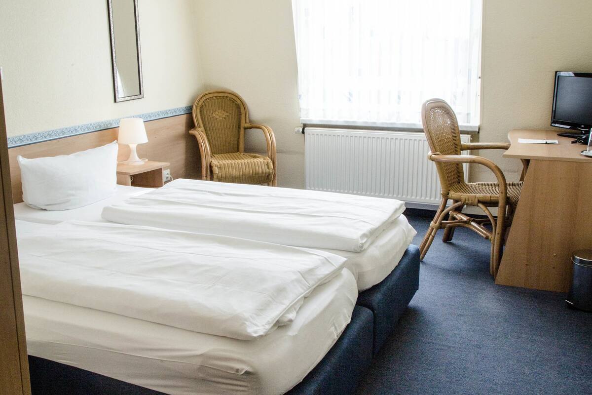 Een hotelkamer met twee bedden, een bureau, een stoel en een televisie.