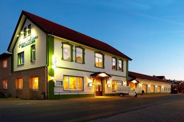 A two-story building with a red roof and green trim, featuring a sign that reads "Hotel". - Akzent Hotel Hubertus (Melle)