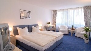 A hotel room with a large bed, two bedside tables, a desk, a chair, and a TV. - Hotel am Klostersee (Sindelfingen)