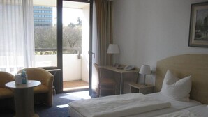 A hotel room with a bed, a desk, a chair, and a small table. - Hotel am Klostersee (Sindelfingen)