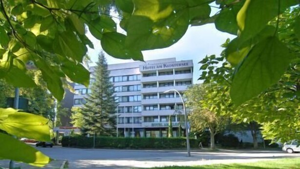 A multi-story hotel with a modern design, featuring a central courtyard and a parking area. - Hotel am Klostersee (Sindelfingen)