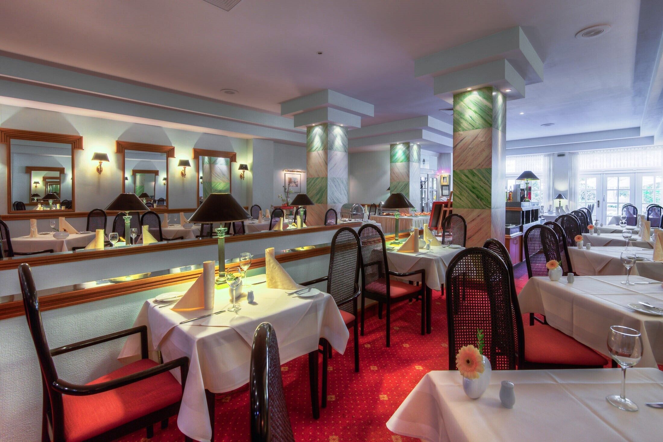 Un restaurante con varias mesas, sillas y un espejo grande en la pared.