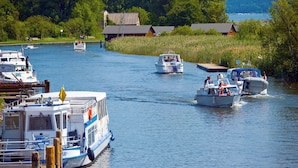 Un río con barcos amarrados en un muelle, rodeado de vegetación y edificios.