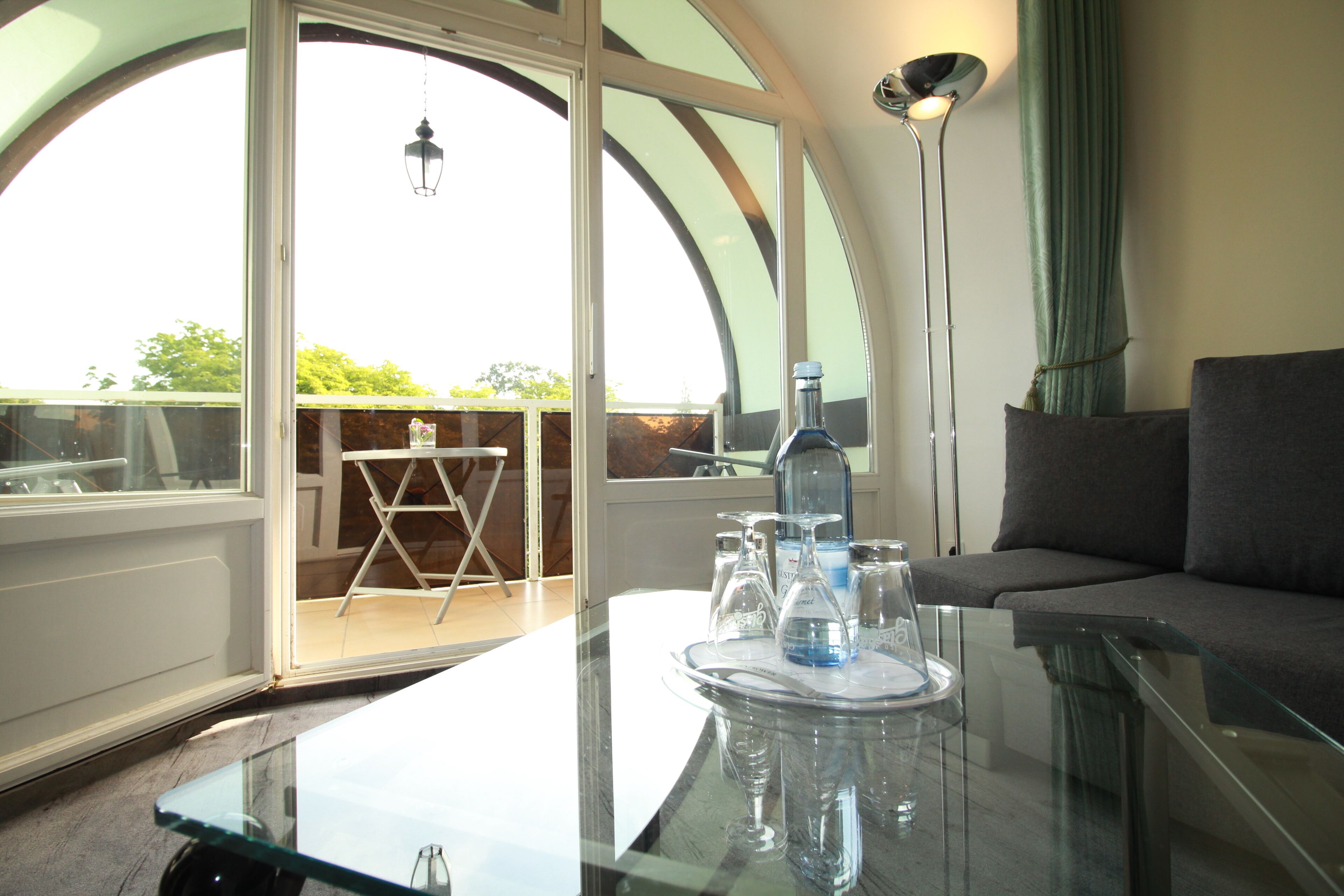 Ein modernes Wohnzimmer mit Glastisch, Sofa und Balkon mit Blick.