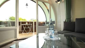Een moderne woonkamer met een glazen tafel, een bank en een balkon met uitzicht.