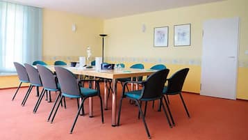 Une salle de conférence avec une longue table et huit chaises, une porte blanche et deux tableaux encadrés au mur.