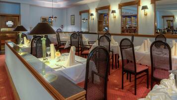 A hotel dining area with tables set for service, chairs, and a counter with a lamp.