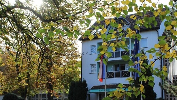 Un hotel con un cartel que dice "PARK HOTEL" frente a un edificio con varias ventanas y balcones.