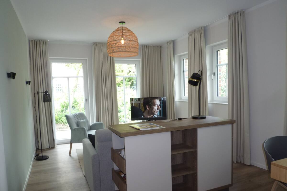 Ein modernes Wohnzimmer mit einer zentralen Insel, einem Fernseher und einer Pendelleuchte.