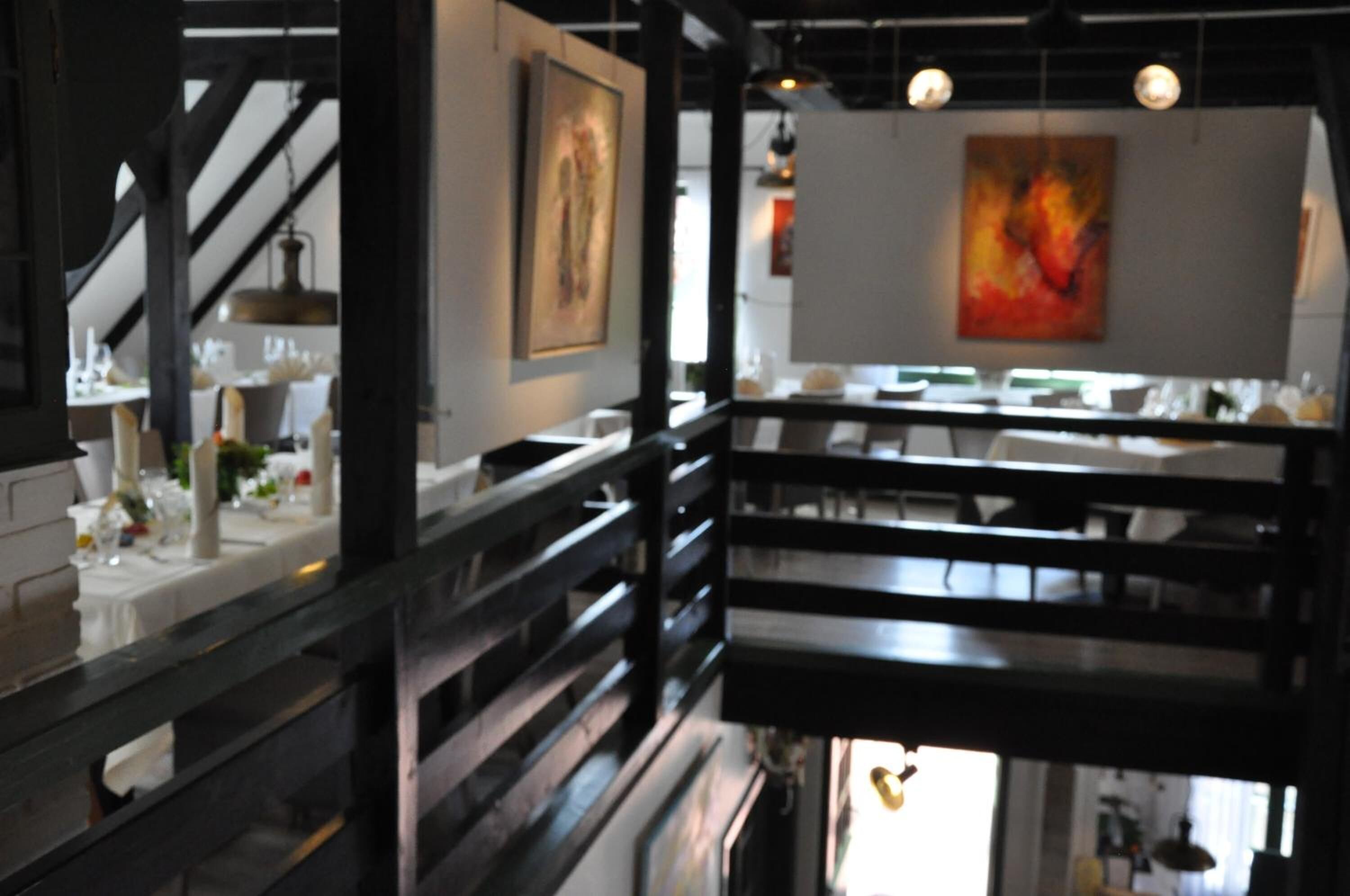 L’intérieur d’un restaurant, avec un escalier, des tables et des œuvres d’art accrochées aux murs.