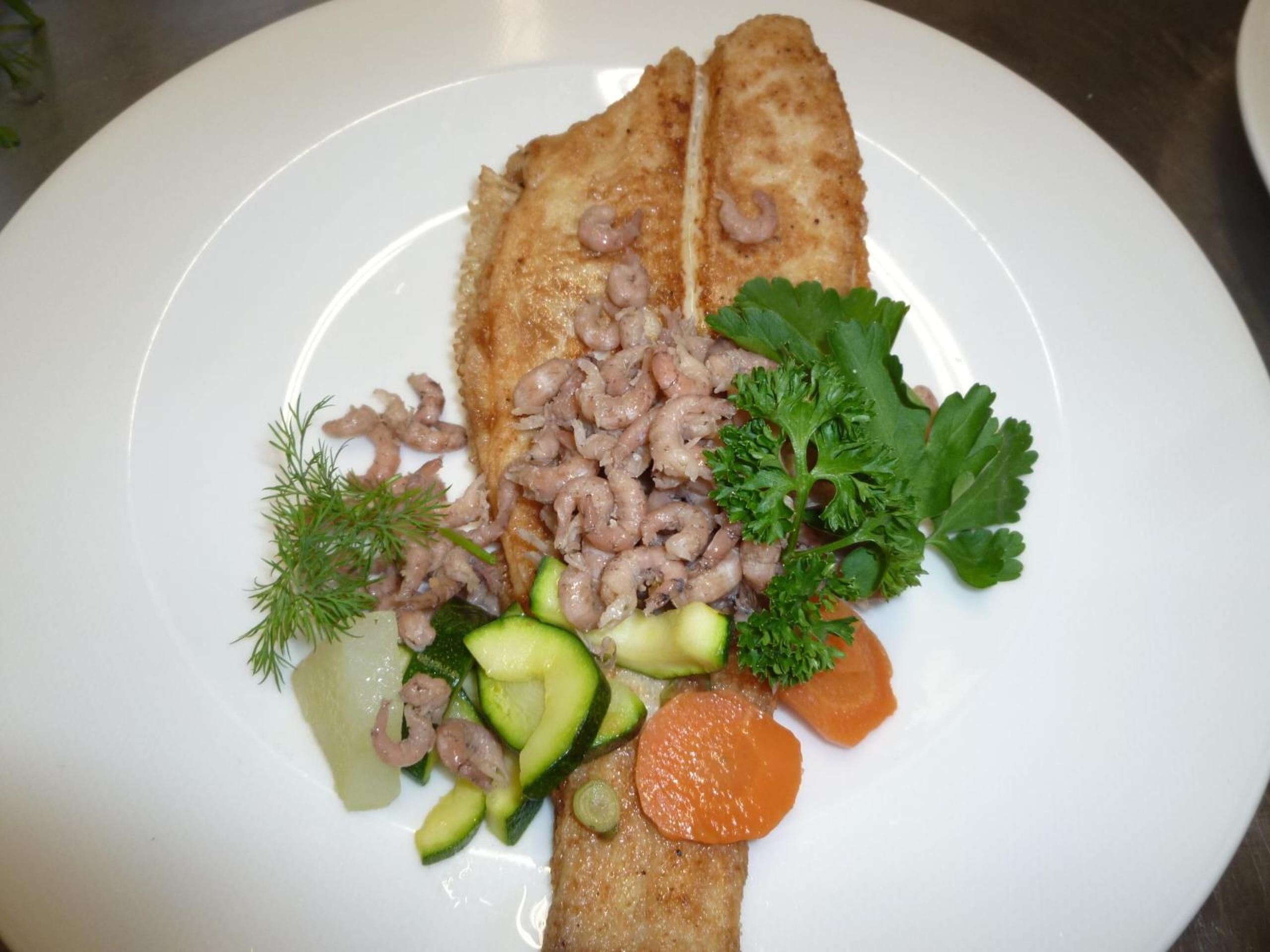 A plate with a piece of breaded fish, mushrooms, and vegetables.