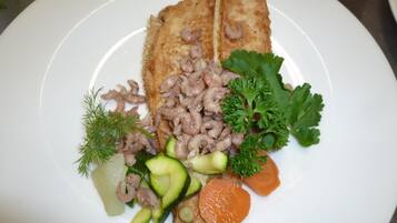 A plate with a piece of breaded fish, mushrooms, and vegetables.