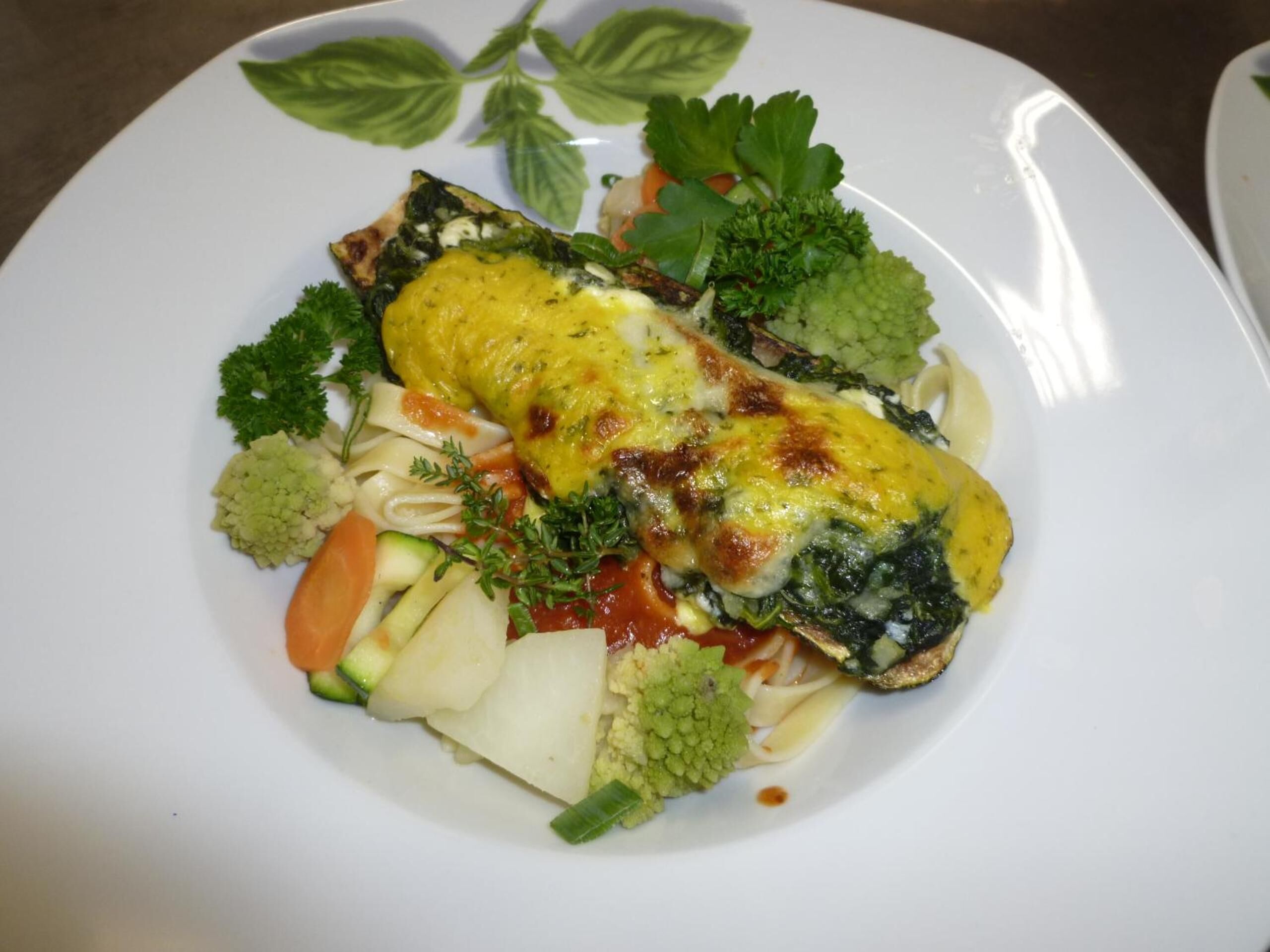 Un plato de comida con una tortilla enrollada, verduras y hierbas.