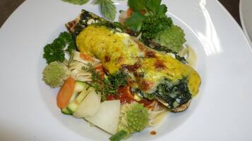 Un plato de comida con una tortilla enrollada, verduras y hierbas.