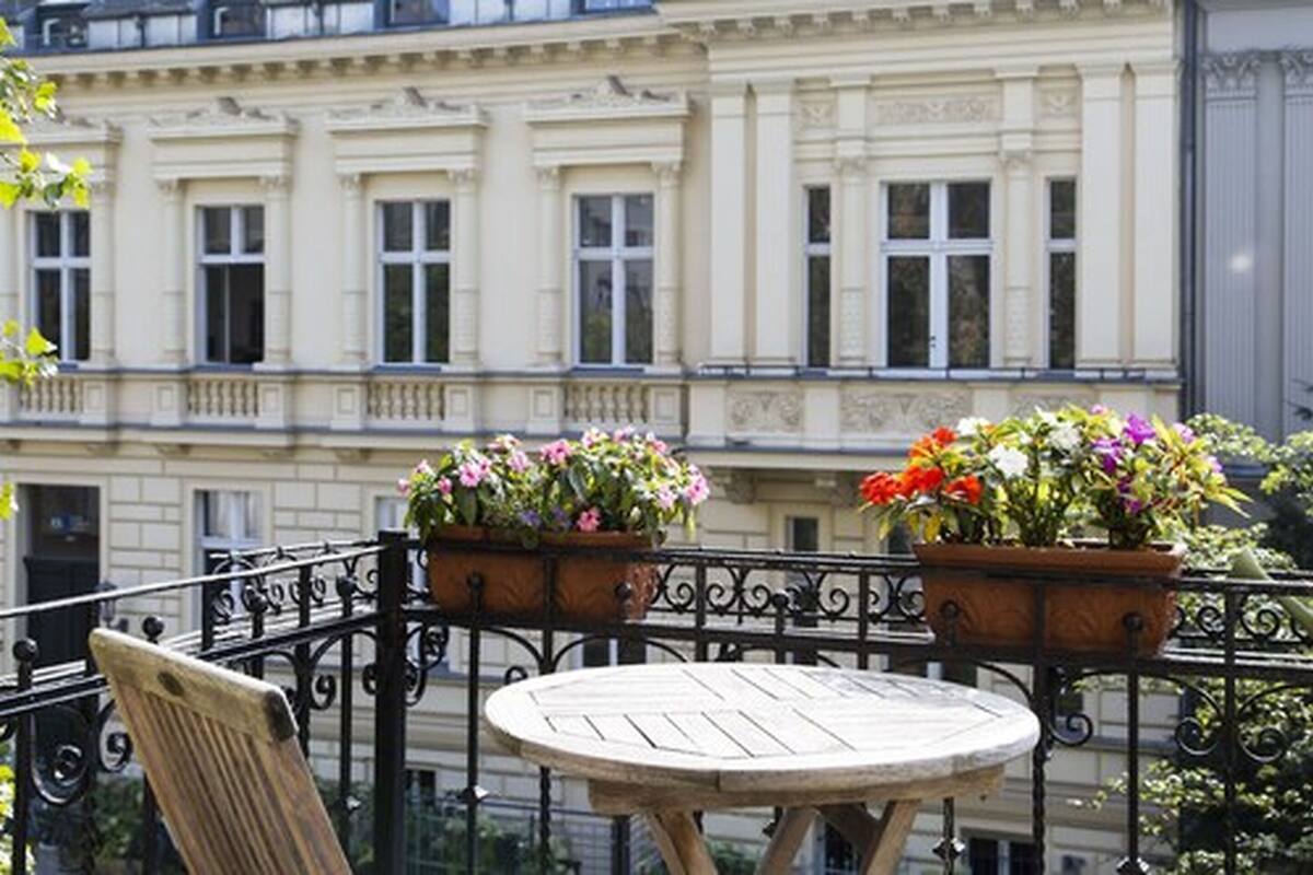 A balcony with a round wooden table and two flower planters.