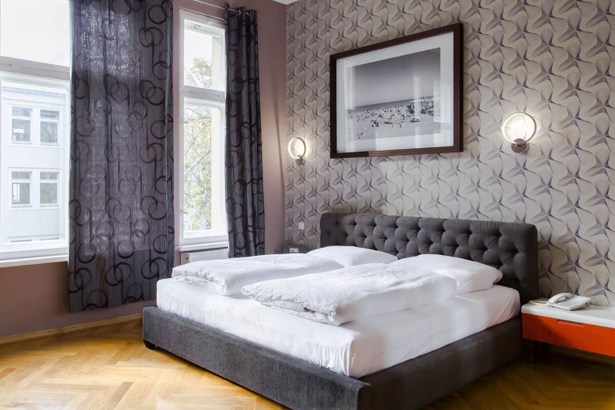 A bedroom with a large bed, a bedside table with a phone, and a framed picture on the wall.
